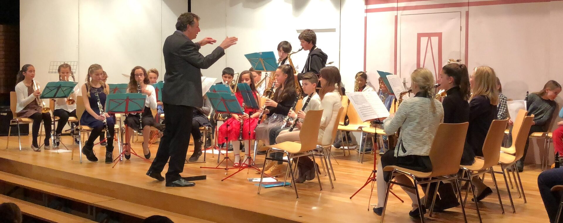Ein Klassenorchester der Primarschule Itschnach spielt auf der Bühne, geleitet von einem Dirigenten.